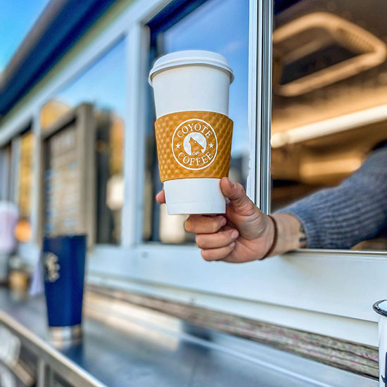 hand holding a coffee to a customer outside the yote wagon