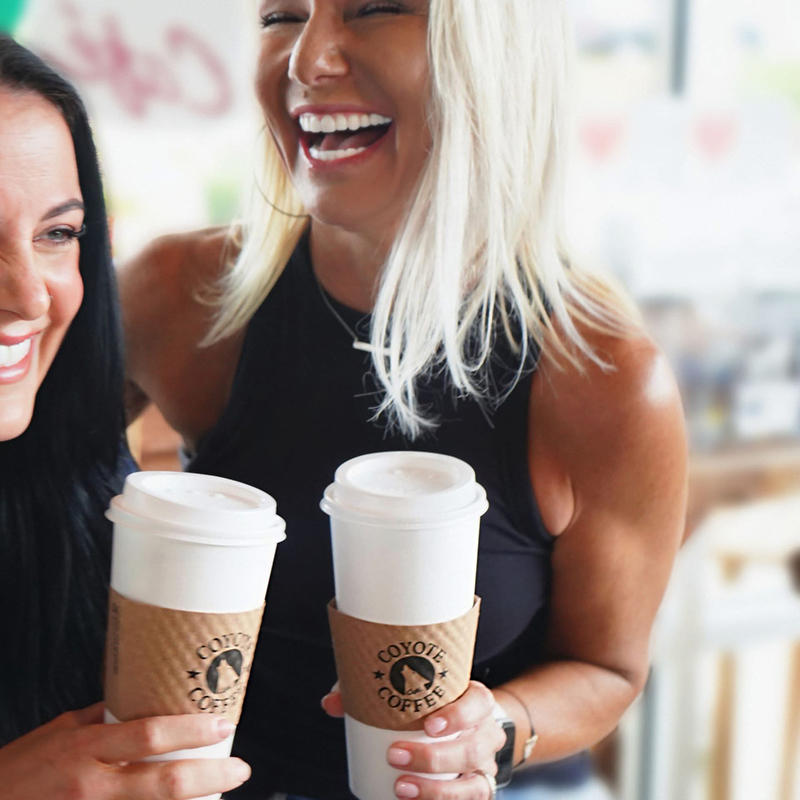 Tunckie and Candace laughing while holding coffees.